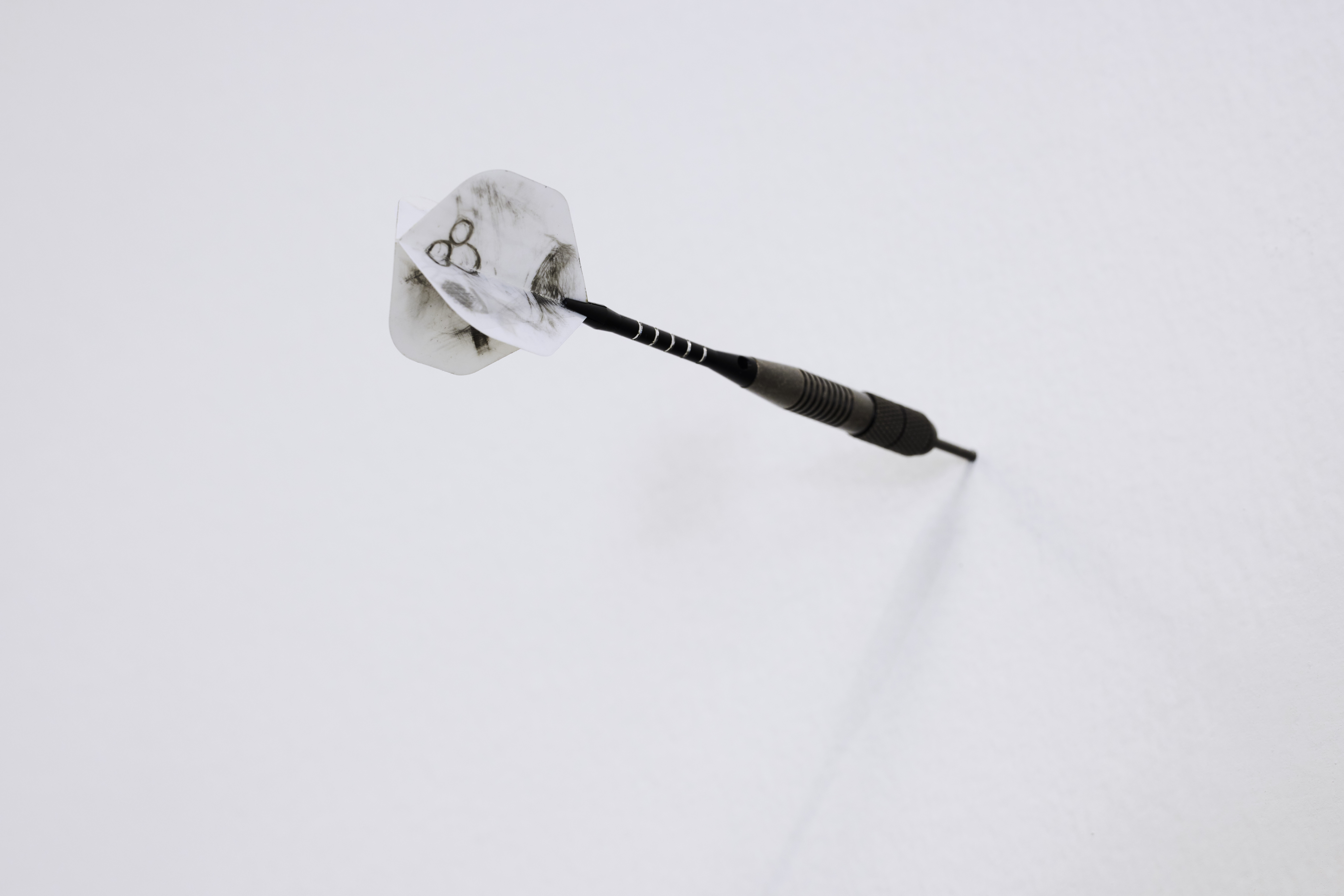 a dart stuck into a white wall